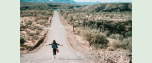 A woman running down a trail toward mountains